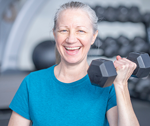 A strong confident older woman holding a dumbbell. laughing 